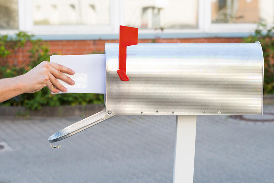 Hand putting letter into the mailbox
